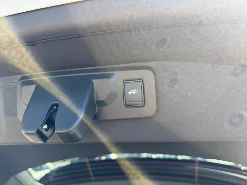 Gros plan sur le bouton d'ouverture du coffre à l'intérieur du hayon du Renault Austral blanc nacré 2025.