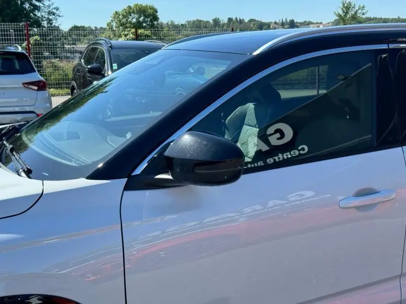 Vue latérale côté gauche du Renault Austral blanc nacré avec toit noir étoilé et rétroviseur noir brillant.