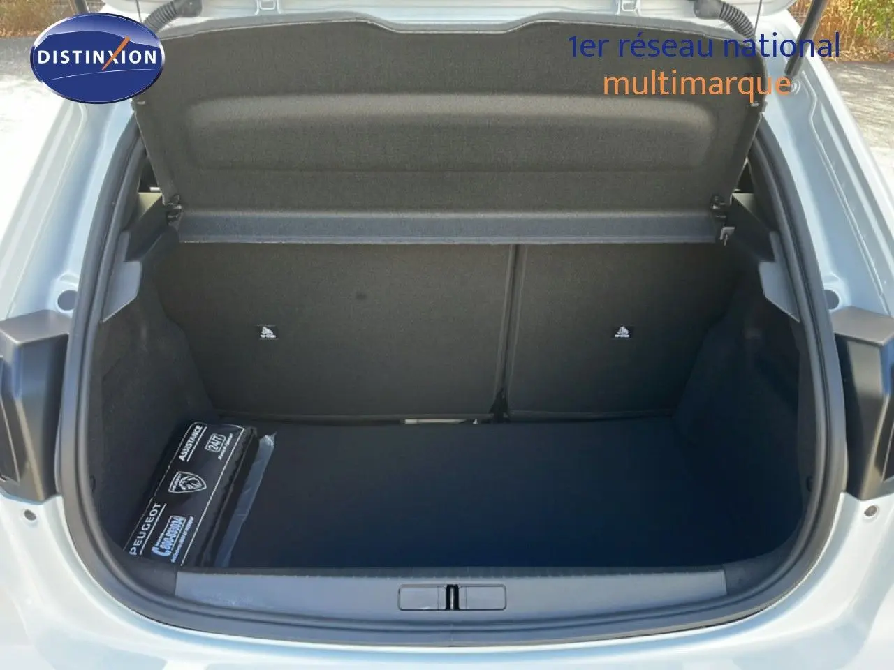 Coffre ouvert vu de l'arrière d'une Peugeot 208 blanche Okenite Metal, montrant un espace de rangement vide et propre.