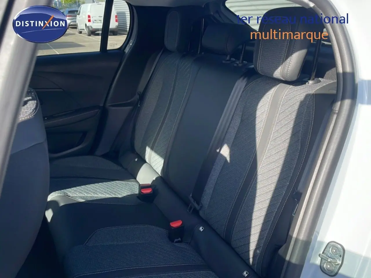 Vue intérieure sur les sièges arrière en tissu gris et noir d'une Peugeot 208 Hybrid blanche, porte arrière ouverte.