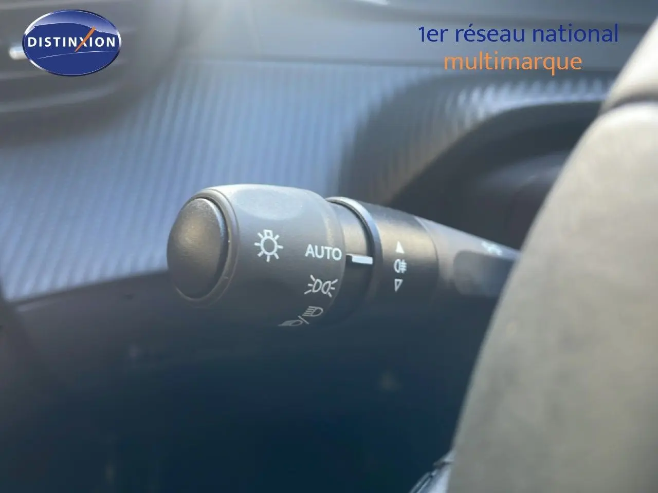 Gros plan sur le commodo des phares à gauche du volant dans l’habitacle d’une Peugeot 208 blanche 2026.