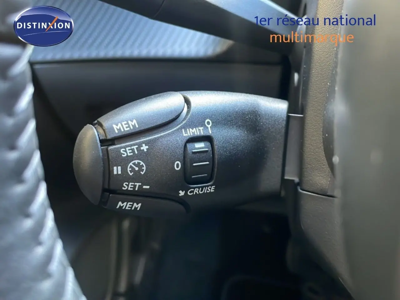 Gros plan sur la commande de régulateur de vitesse au volant d’une Peugeot 208 Hybrid 110ch blanche.
