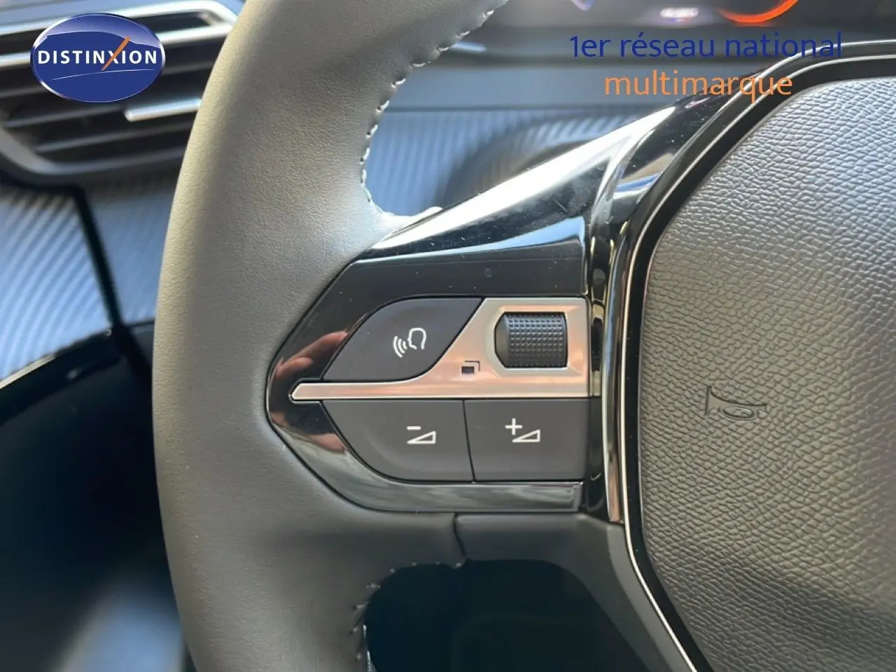 Gros plan sur les commandes gauche du volant noir d’une Peugeot 208 Hybrid blanche, avec boutons de volume et commande vocale.