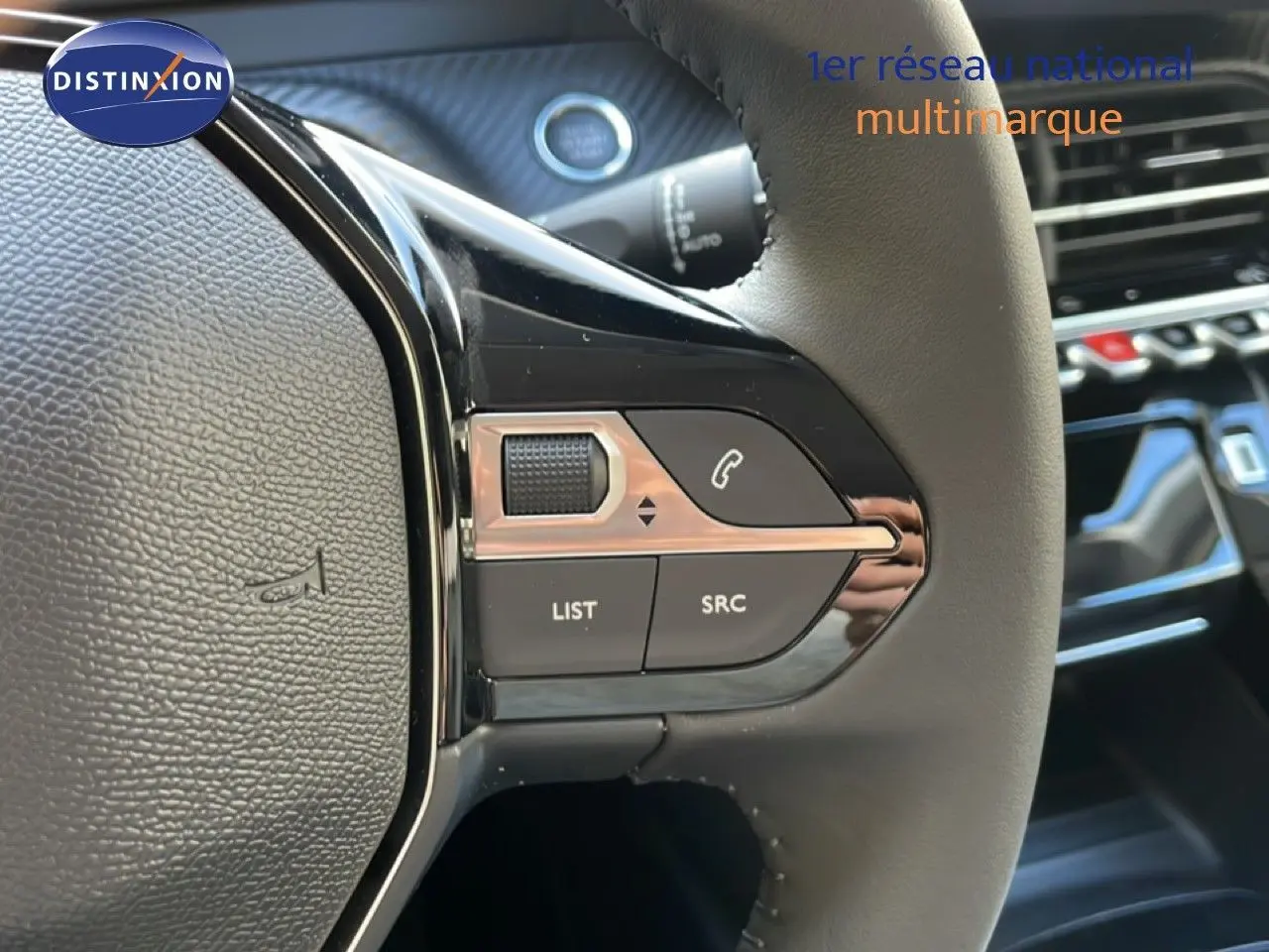 Gros plan sur les commandes gauche du volant en cuir noir du Peugeot 208 Hybrid blanc, avec boutons multifonctions et molette.