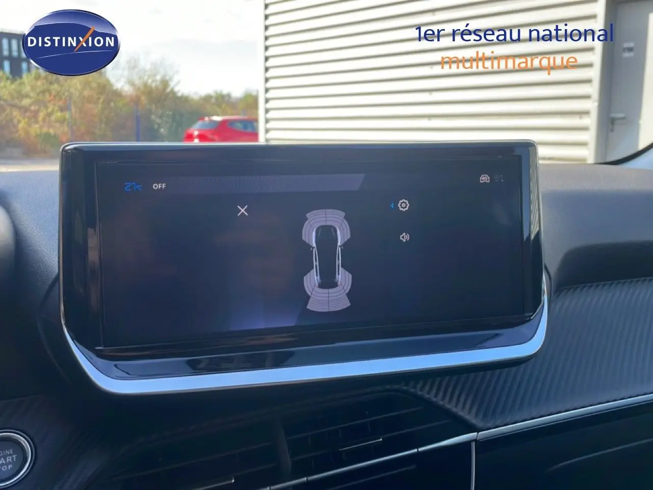 Écran tactile central affichant l'aide au stationnement dans l'habitacle d'une Peugeot 208 blanche.