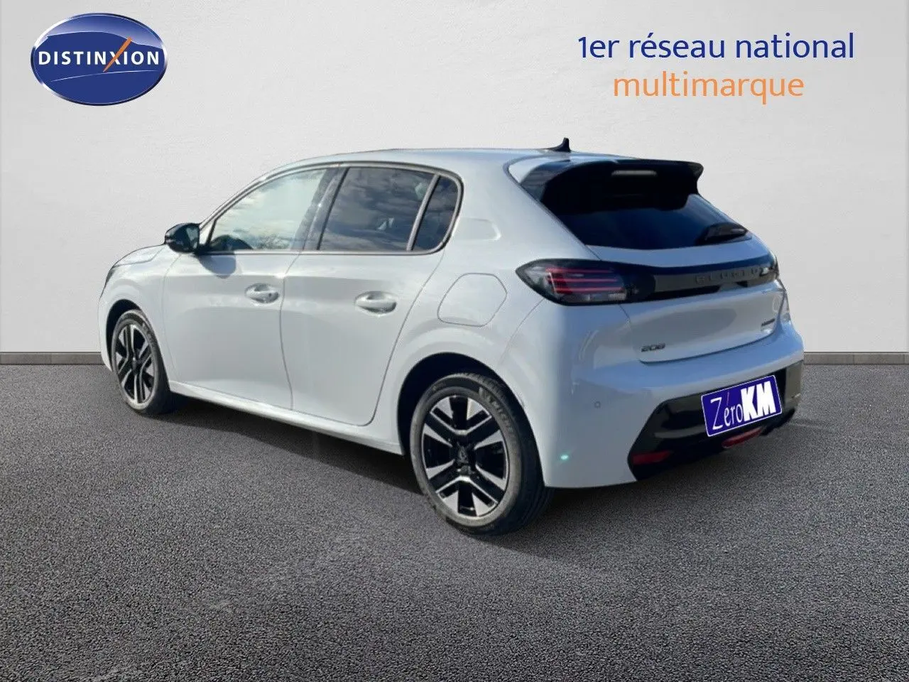 Vue 3/4 arrière droite d'une Peugeot 208 hybride blanche Okenite Metal avec jantes noires et détails noirs au niveau du hayon.