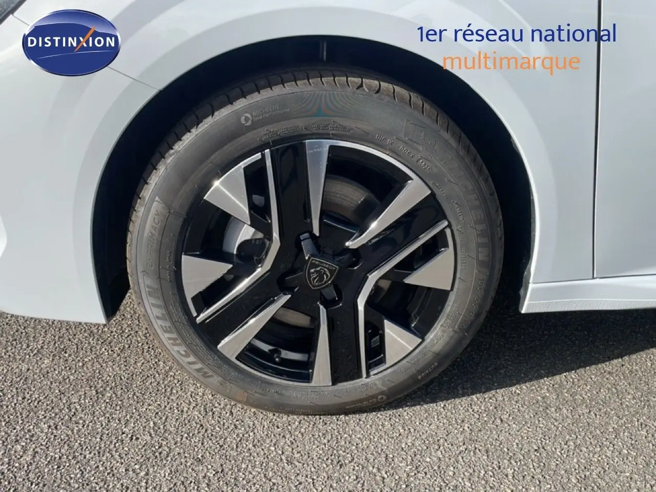 Gros plan sur la roue avant gauche de la Peugeot 208 blanche, mettant en valeur la jante noire et argent au design moderne.