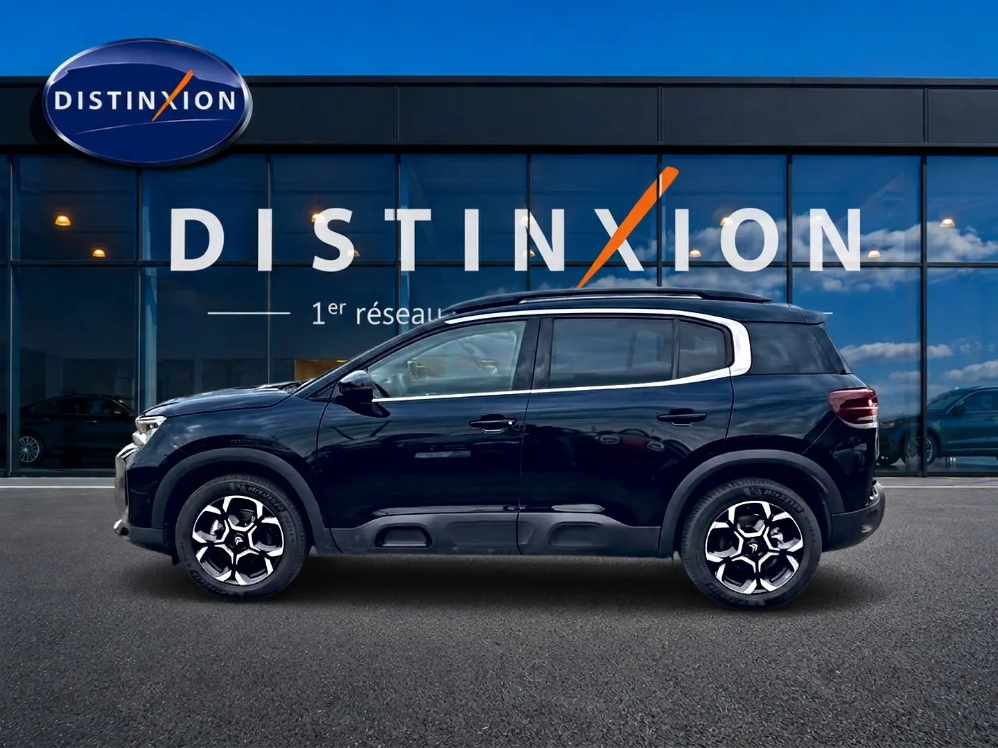 Profil côté gauche du Citroën C5 Aircross noir 2025 avec jantes alu et barres de toit visibles devant une vitrine Distinxion.