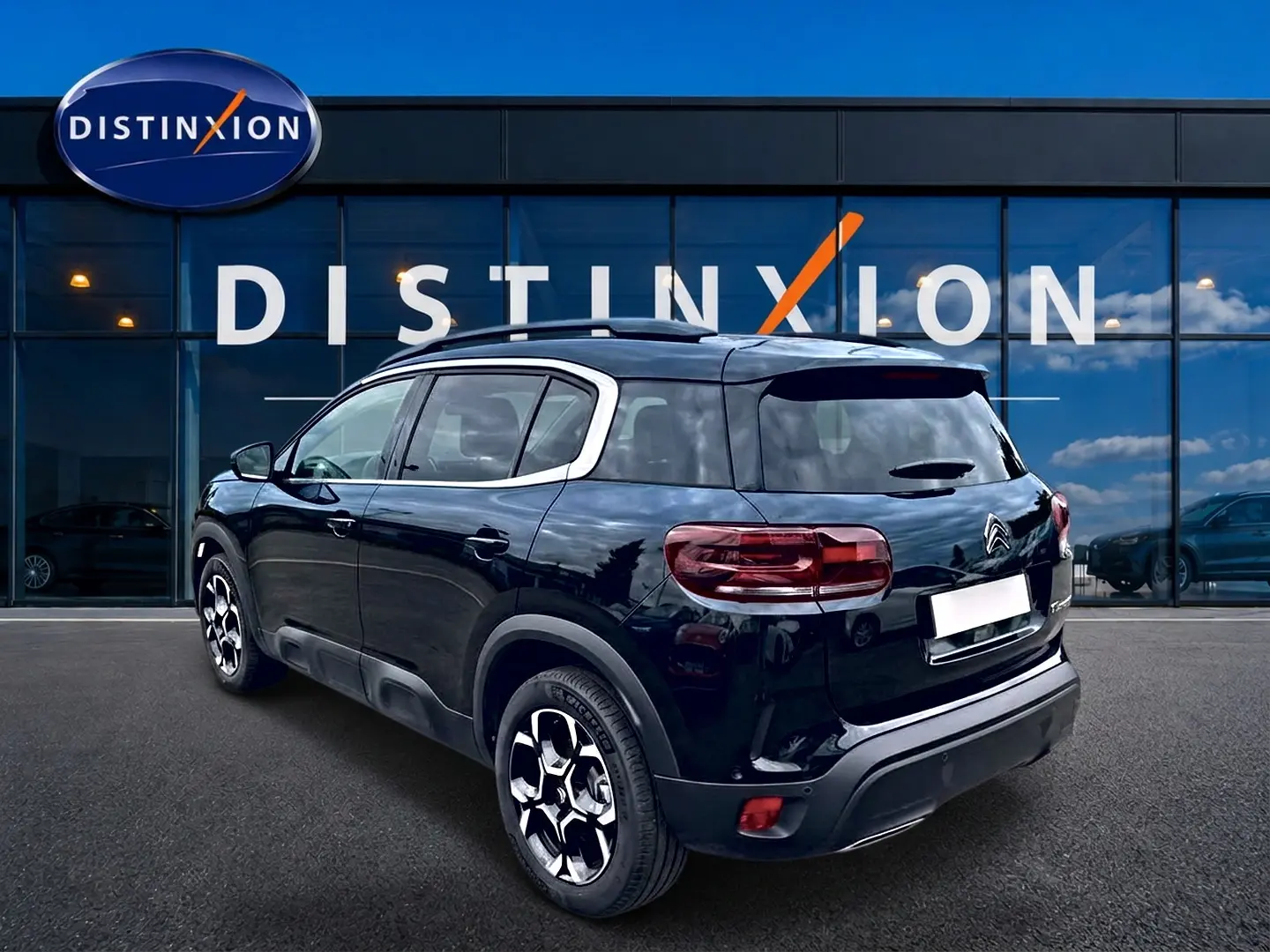 Vue 3/4 arrière droite d'un Citroën C5 Aircross noir avec jantes alu et vitres arrière teintées, devant une vitrine Distinxion.