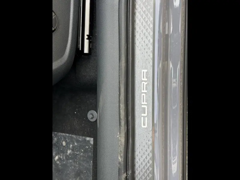 Gros plan sur la plaque de seuil de porte gris Graphène personnalisé avec logo CUPRA visible côté conducteur.