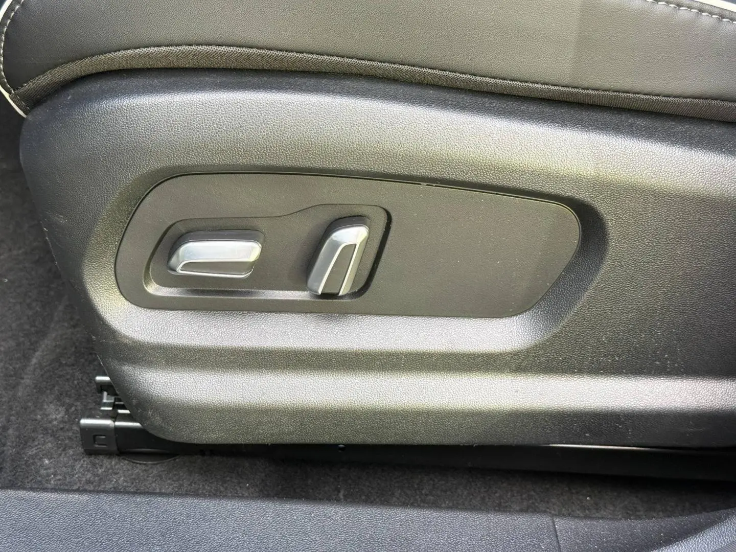 Gros plan sur les commandes électriques de réglage du siège conducteur en cuir synthétique noir du JAECOO J5 Phantom Grey.