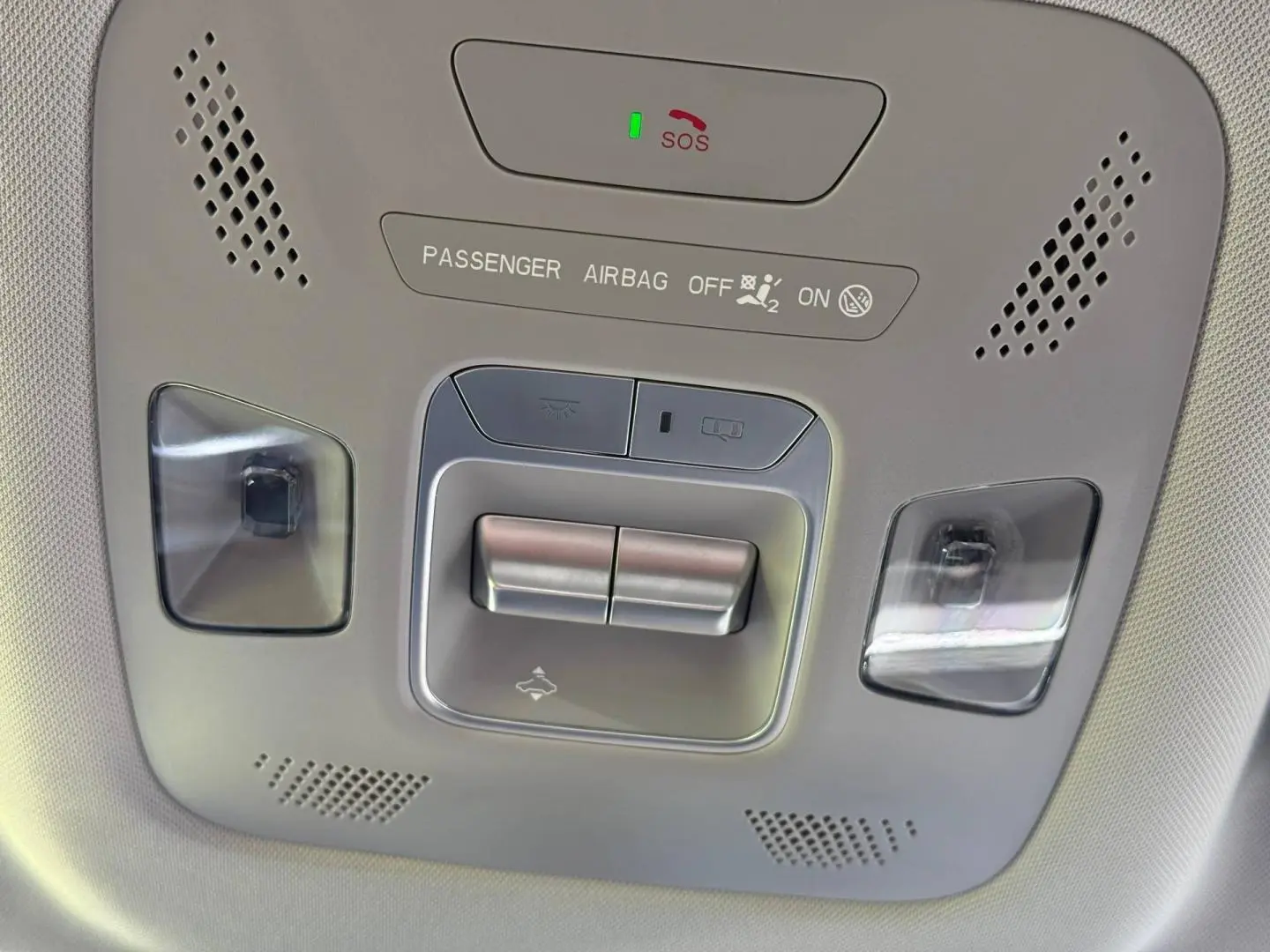 Vue en contre-plongée du panneau de commandes au plafond du JAECOO J5, avec éclairage intérieur et bouton SOS visible.
