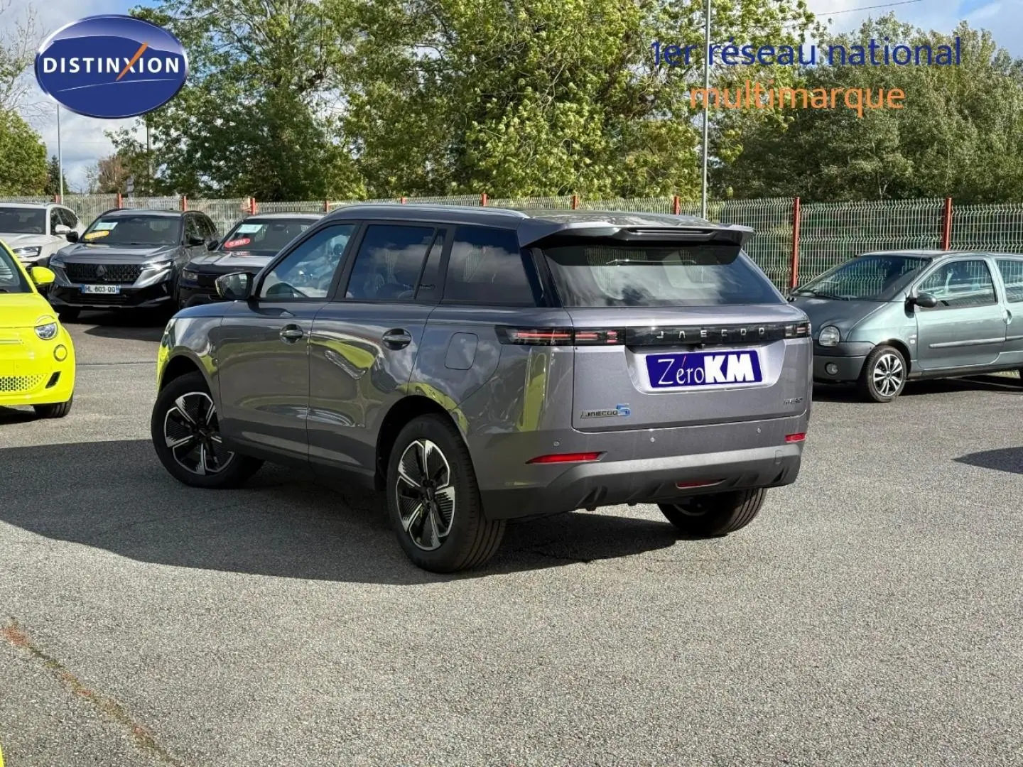 Vue 3/4 arrière droite du JAECOO J5 Phantom Grey métal avec jantes alu et toit noir dans un parking extérieur.