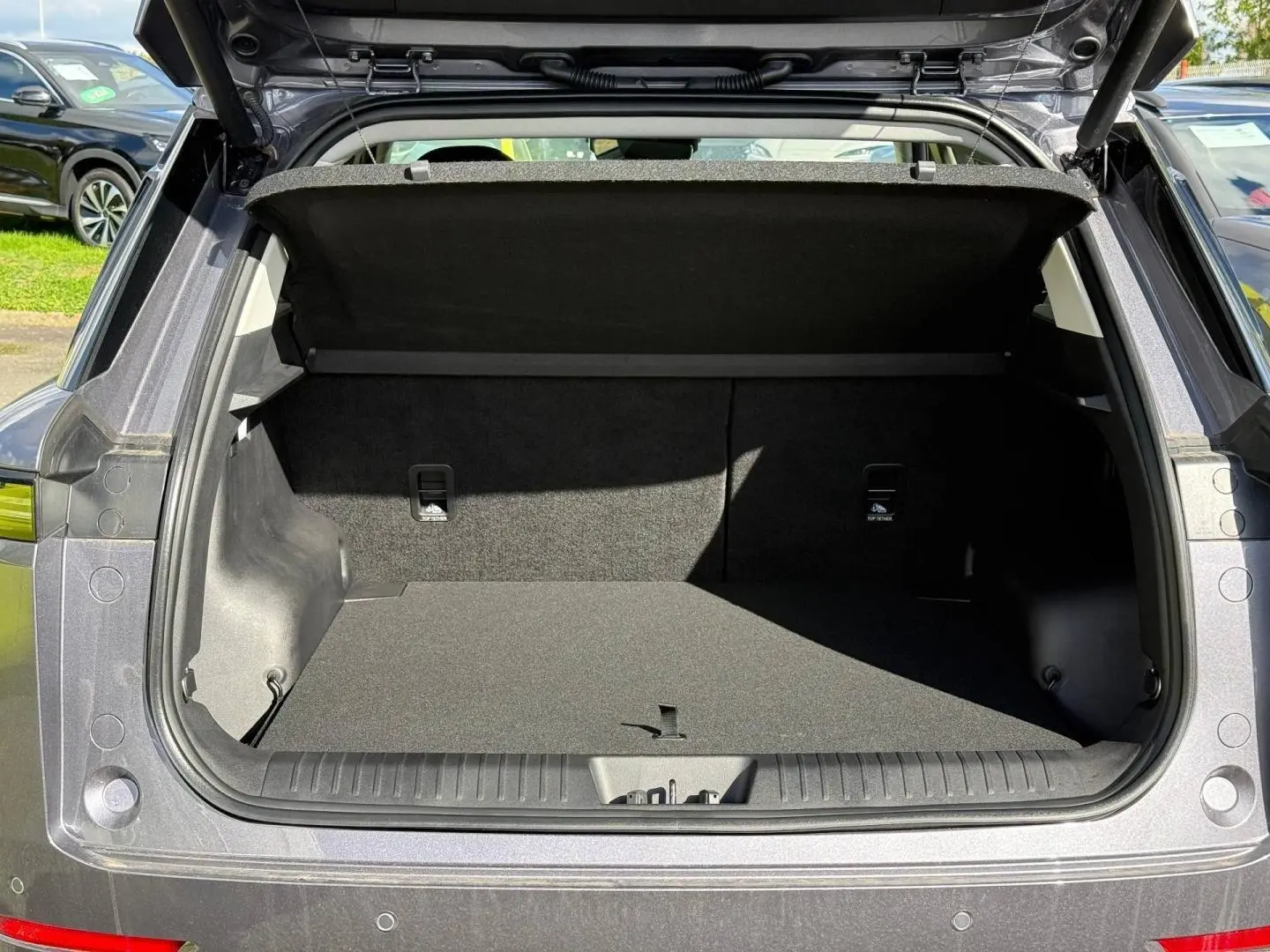 Coffre ouvert d’un JAECOO J5 Phantom Grey métal vu de l’arrière, montrant l’espace de chargement vide et la tablette cache-bagages.