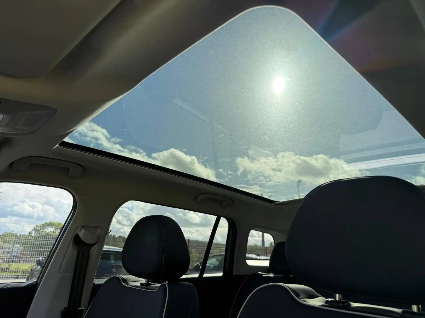 Vue intérieure du toit panoramique en verre du JAECOO J5 Phantom Grey, avec sièges avant en cuir noir visibles de côté gauche.