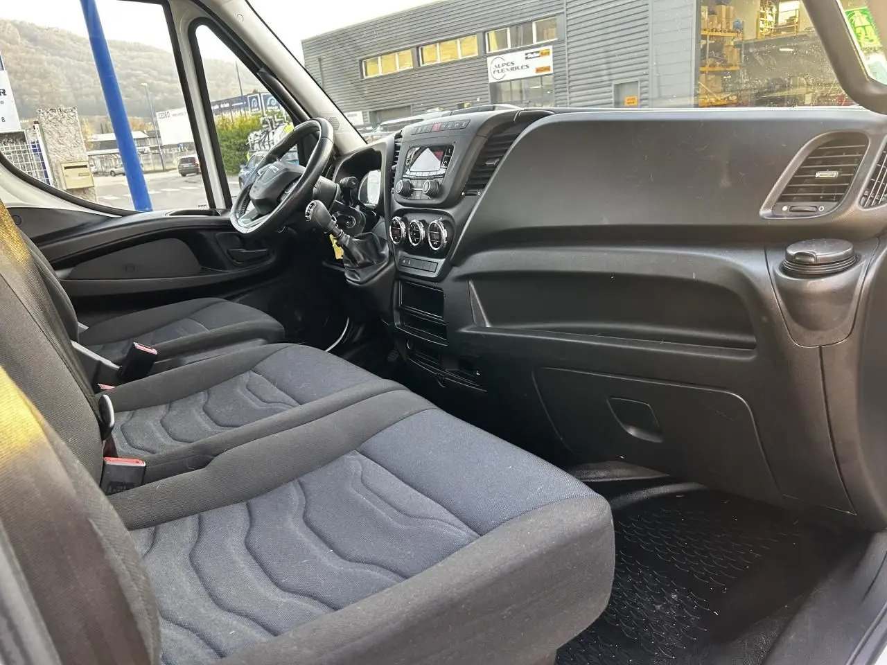 Intérieur de l'IVECO Daily 2020 vu côté passager, montrant la banquette noire et le tableau de bord fonctionnel.
