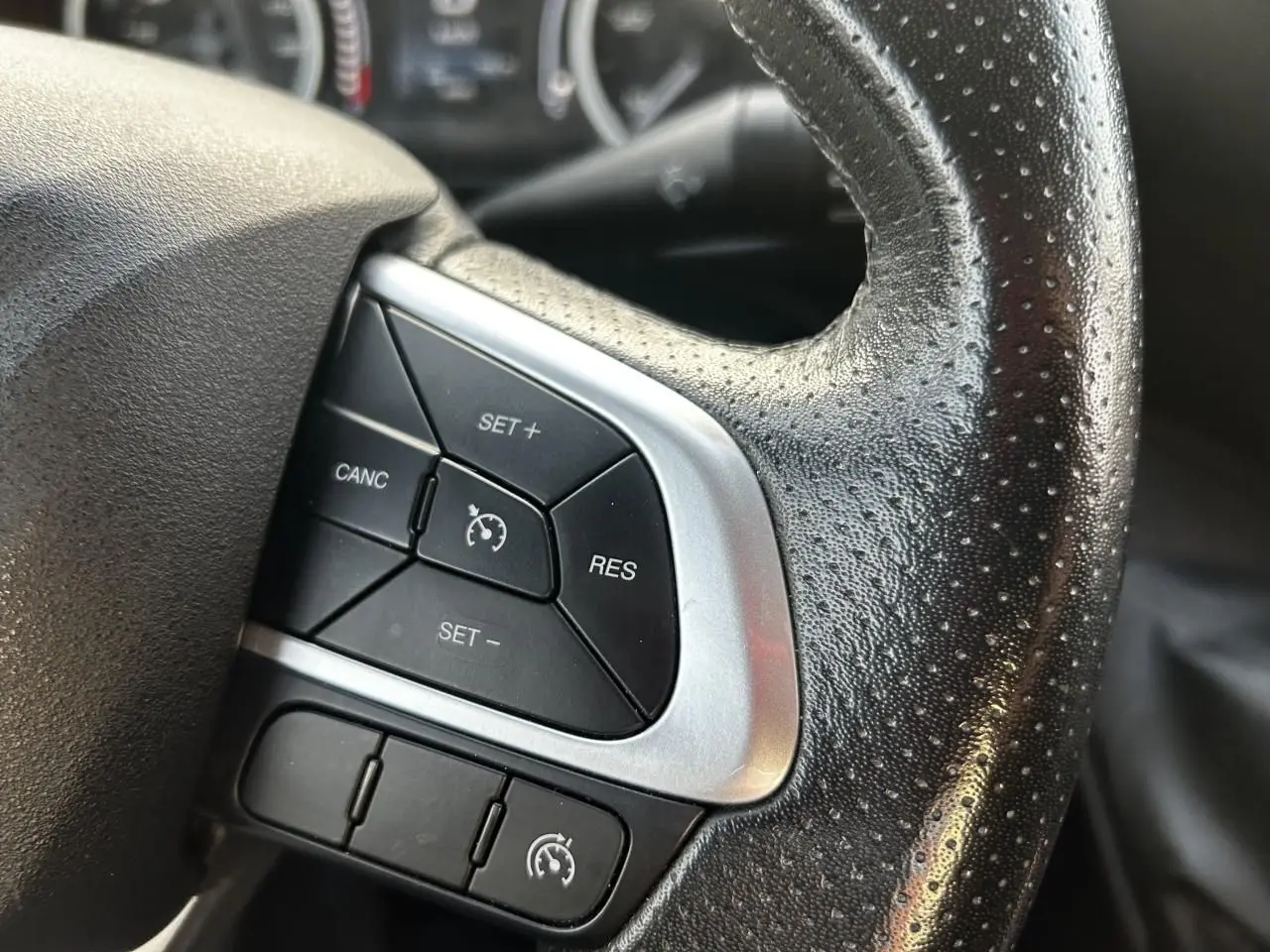 Gros plan sur les commandes de régulateur de vitesse au volant en cuir noir perforé de l'Iveco Daily blanc 2020.