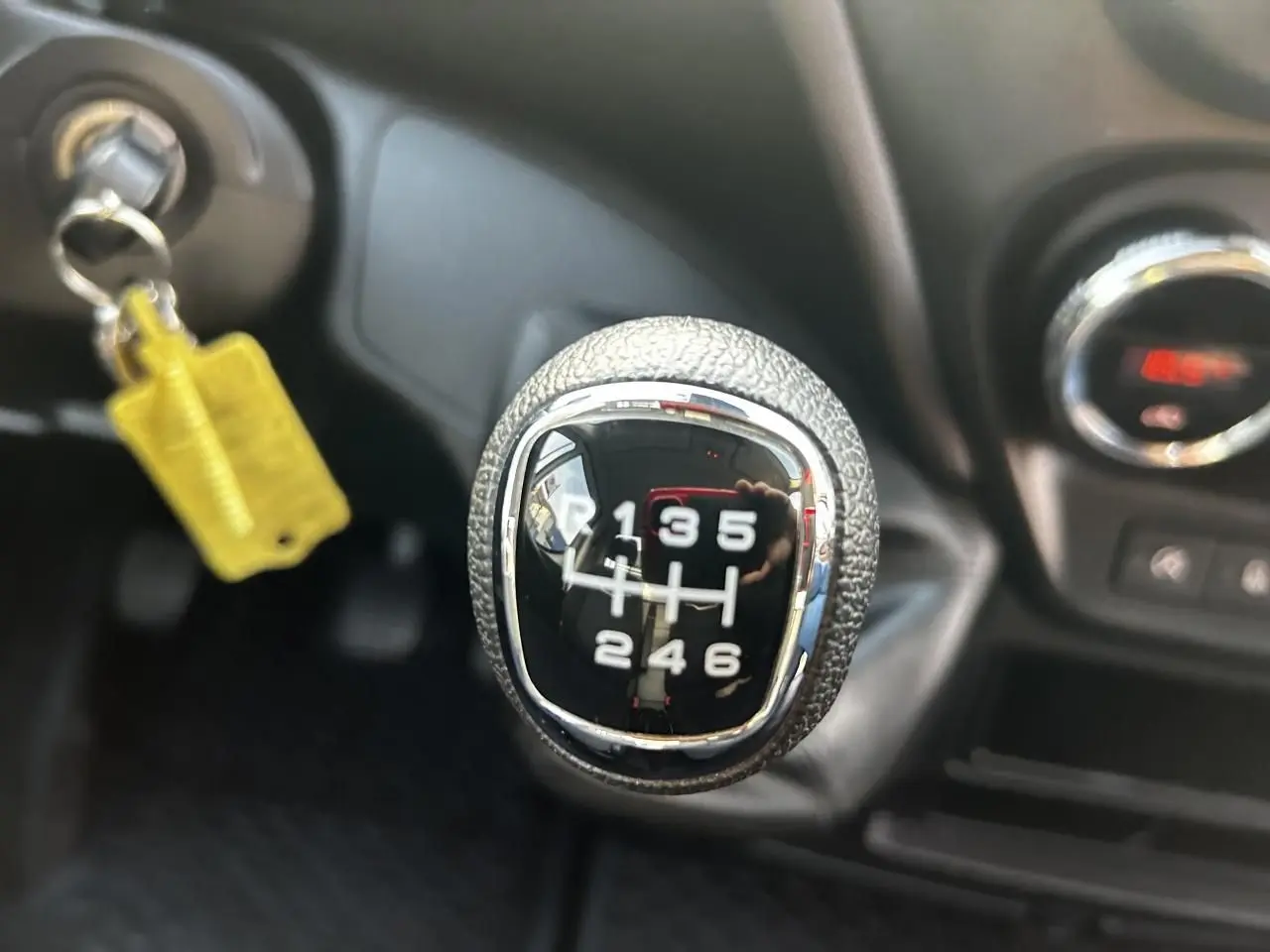 Gros plan sur le levier de vitesses manuel du Iveco Daily blanc 2020, avec clé insérée et tableau de bord en arrière-plan.