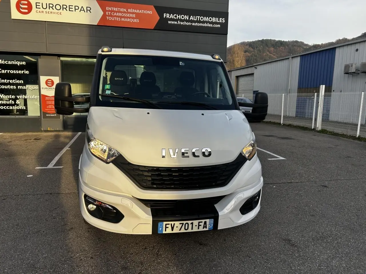 Vue de face d'un utilitaire Iveco Daily blanc immatriculé en France, stationné devant un garage Eurorepar.