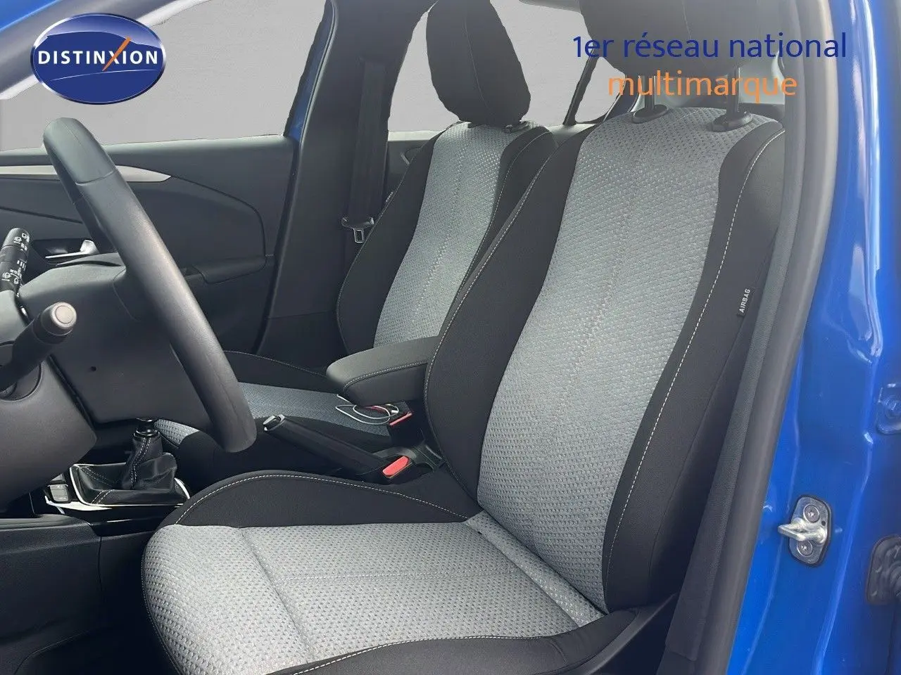 Intérieur avant de l'Opel Corsa 2025 bleu voltaik, sièges tissu gris noir et volant côté gauche visible.