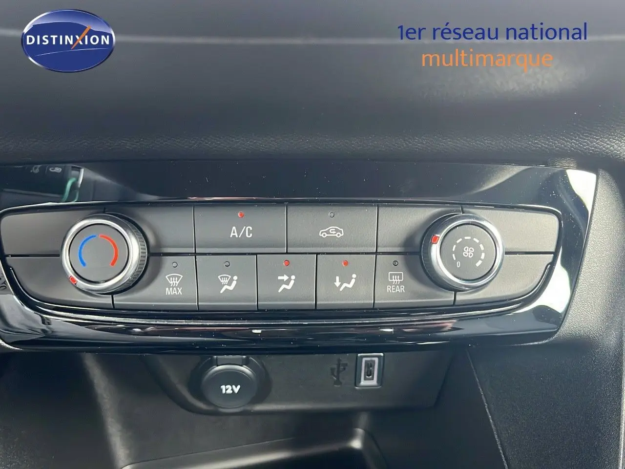 Tableau de bord de l'Opel Corsa bleu voltaik métal 2025 montrant les commandes de climatisation et prise 12V.