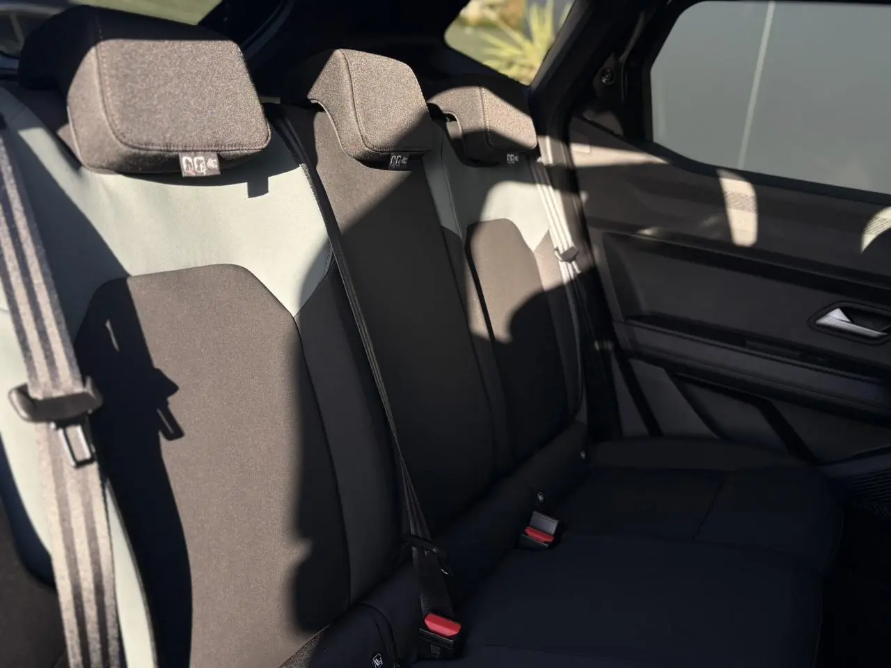 Vue latérale droite de la banquette arrière noire et grise du Dacia Duster 2026 avec ceintures de sécurité et appuie-têtes.