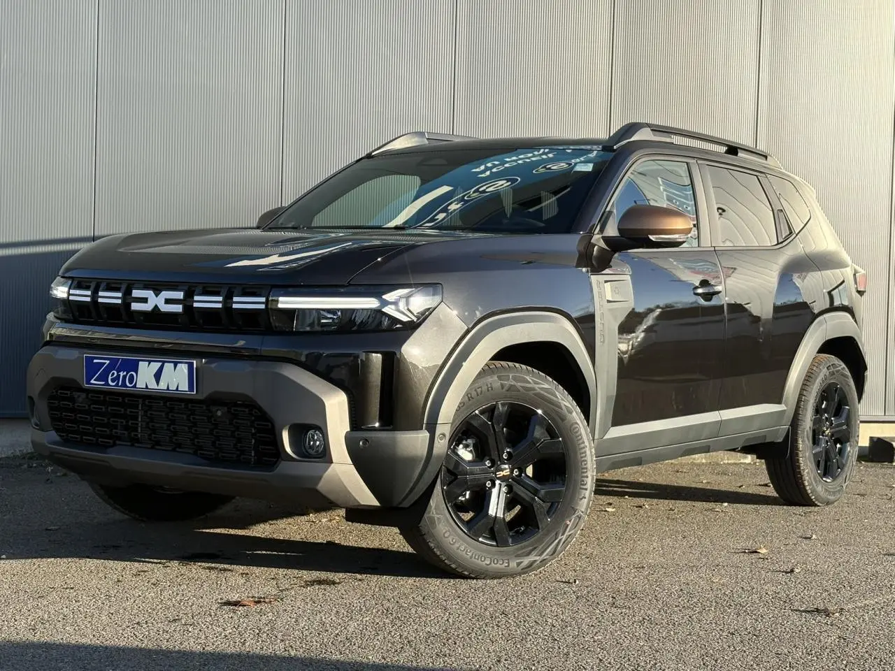 Dacia Duster noir nacré en 3/4 avant droit, avec jantes alliage noires et coques de rétroviseur brun cuivré.