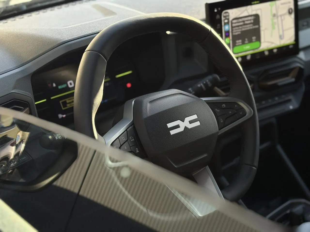Vue rapprochée du volant noir du Dacia Duster 2026 avec tableau de bord digital et écran tactile GPS.