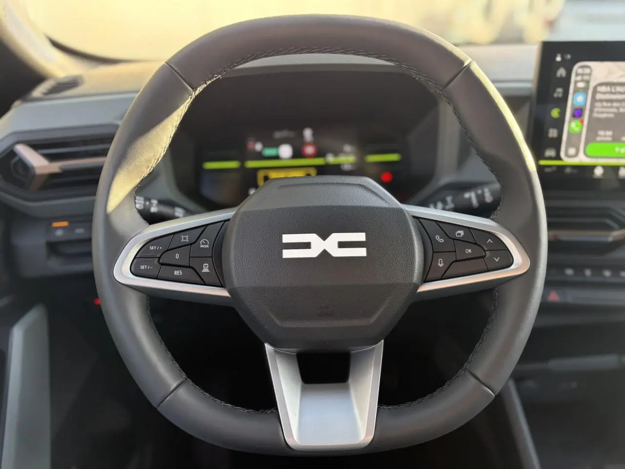 Gros plan sur le volant noir du Dacia Duster 2026 avec commandes intégrées et tableau de bord digital en arrière-plan.