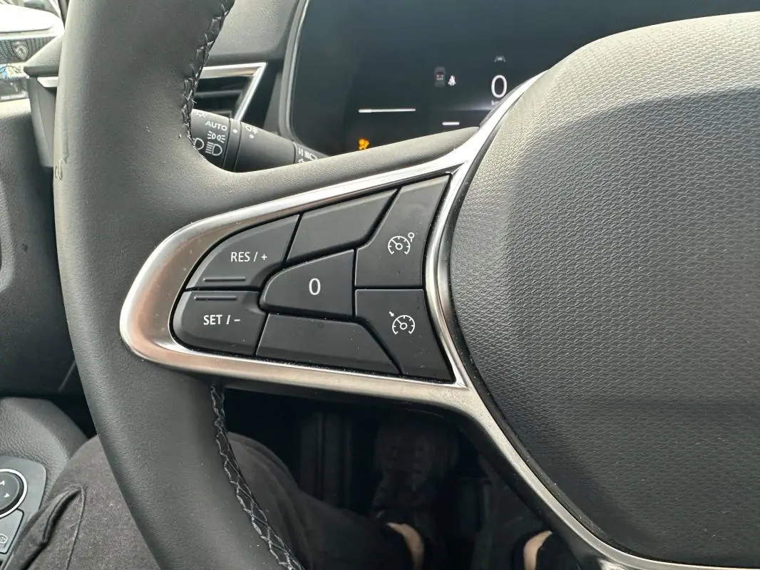 Gros plan sur les commandes du régulateur de vitesse au volant noir de la Renault Clio V dCi 100 Evolution 2025.