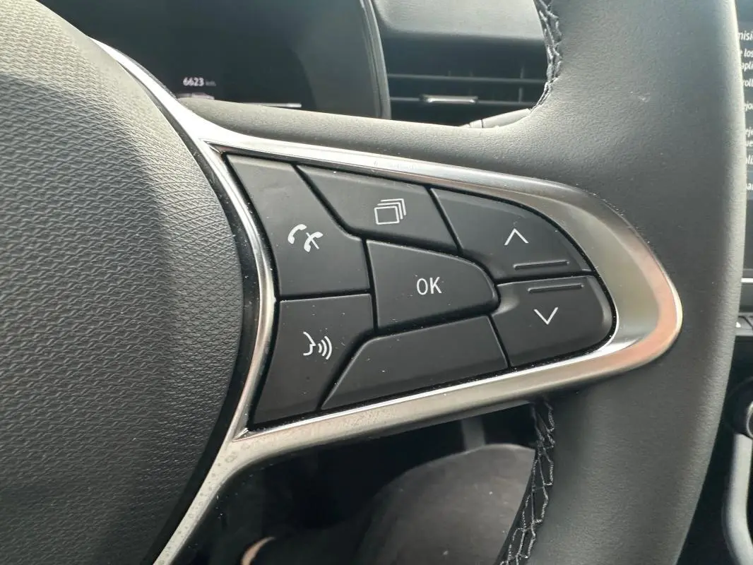 Gros plan sur les commandes multifonctions à droite du volant d’une Renault Clio noire, version V dCi 100 Evolution.