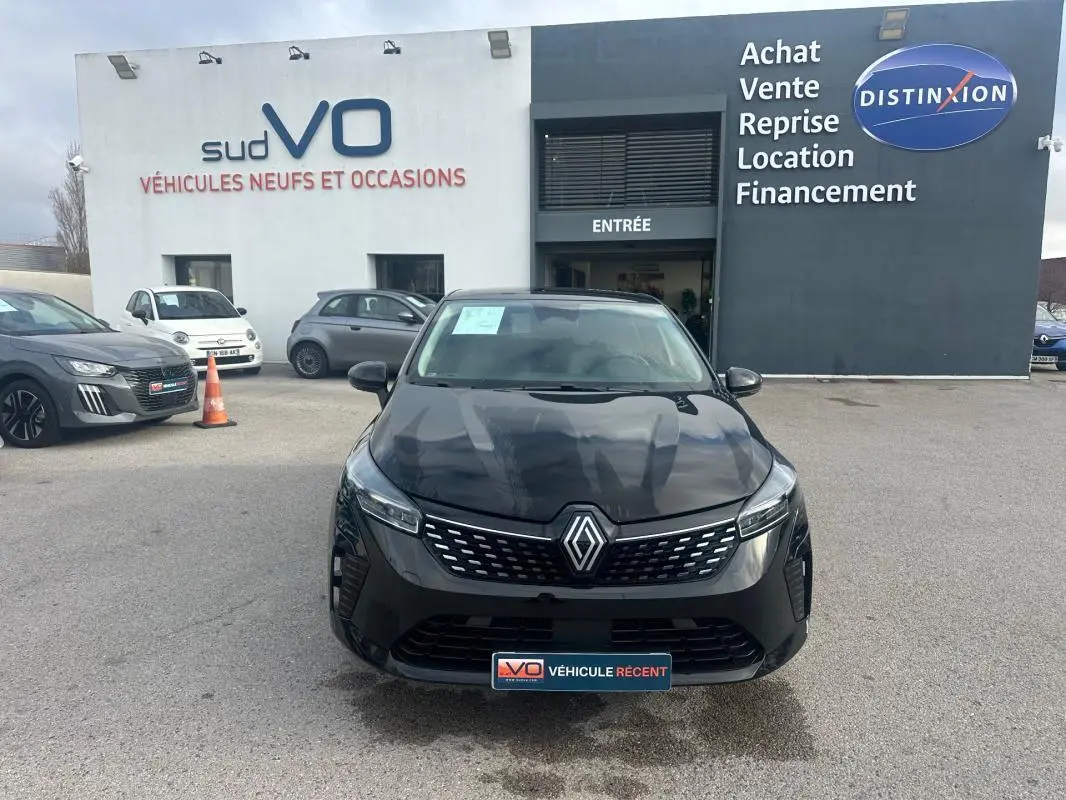 Vue avant d'une Renault Clio V dCi 100 Evolution noire stationnée devant un concessionnaire avec calandre distinctive.