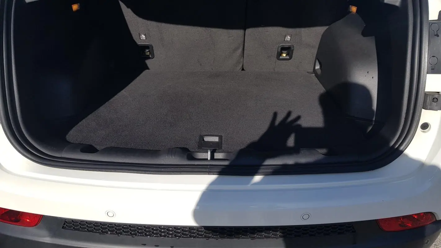 Coffre ouvert vu de l'arrière d'un Jeep Compass blanc 2024, montrant l'espace de chargement vide et tapis noir.