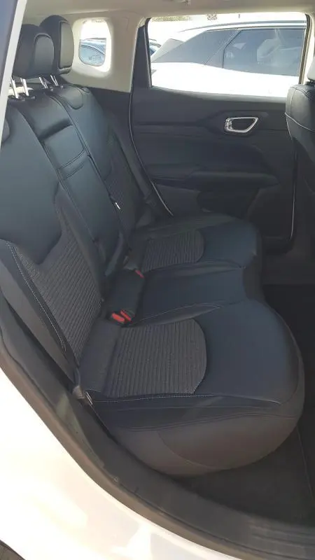 Vue intérieure côté gauche des sièges arrière noirs du Jeep Compass 2024 blanc, avec ceinture et appuie-têtes visibles.