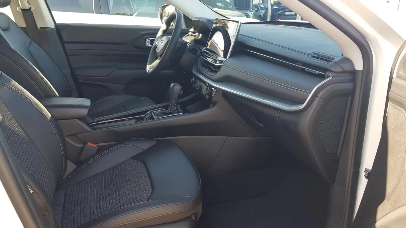 Vue intérieure côté passager du Jeep Compass blanc 2024, montrant sièges noirs, console centrale et écran tactile.