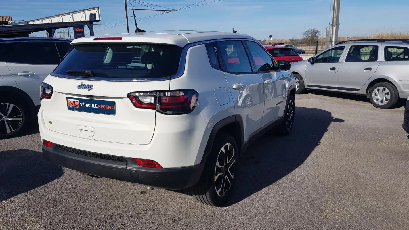 Jeep Compass blanc vu en 3/4 arrière droit, avec jantes alliage 18 pouces et feux arrière LED.
