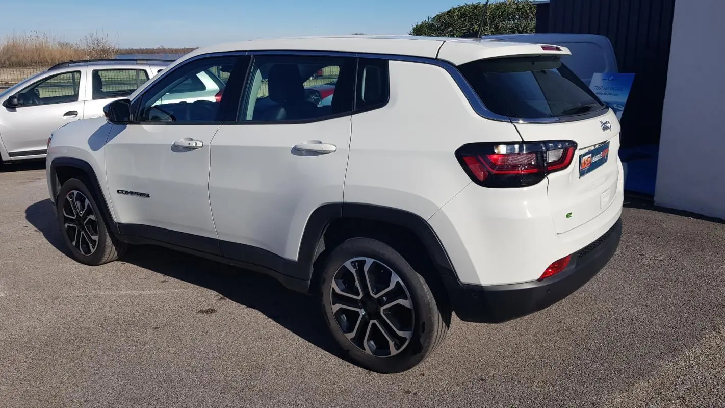 Vue 3/4 arrière gauche d'un Jeep Compass blanc 2024 avec jantes alliage 18 pouces et feux arrière LED.