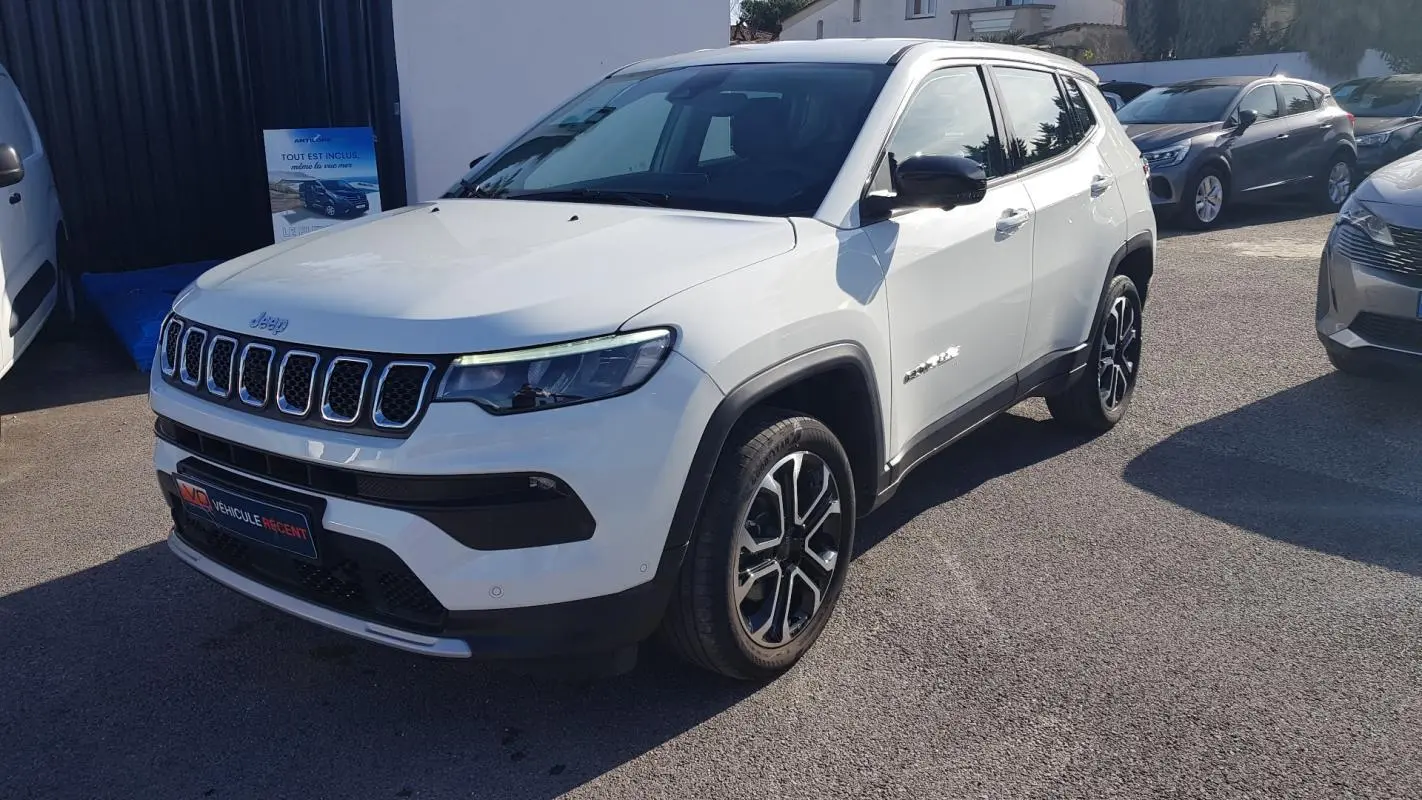 Jeep Compass blanc en 3/4 avant droit, avec jantes alliage 18 pouces et calandre distinctive à sept fentes.