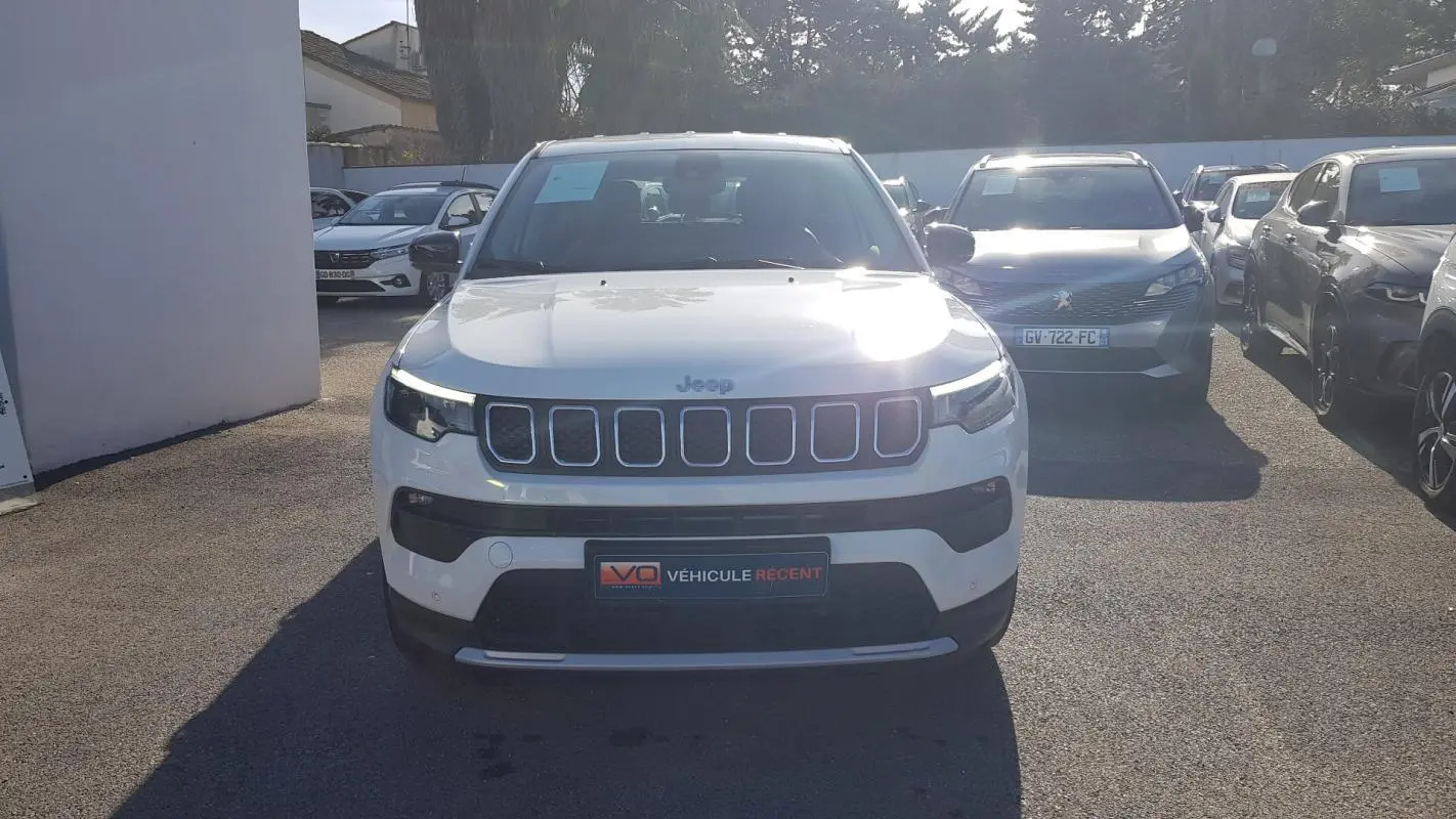 Vue frontale d'un Jeep Compass blanc 2024 avec calandre à sept fentes et phares LED allumés.