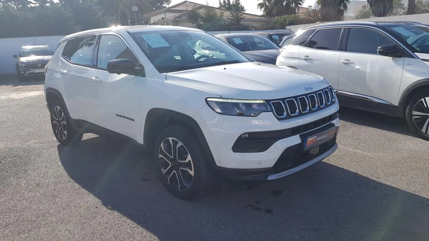 Jeep Compass blanc en 3/4 avant droit, avec jantes alliage 18 pouces et calandre distinctive à sept fentes.