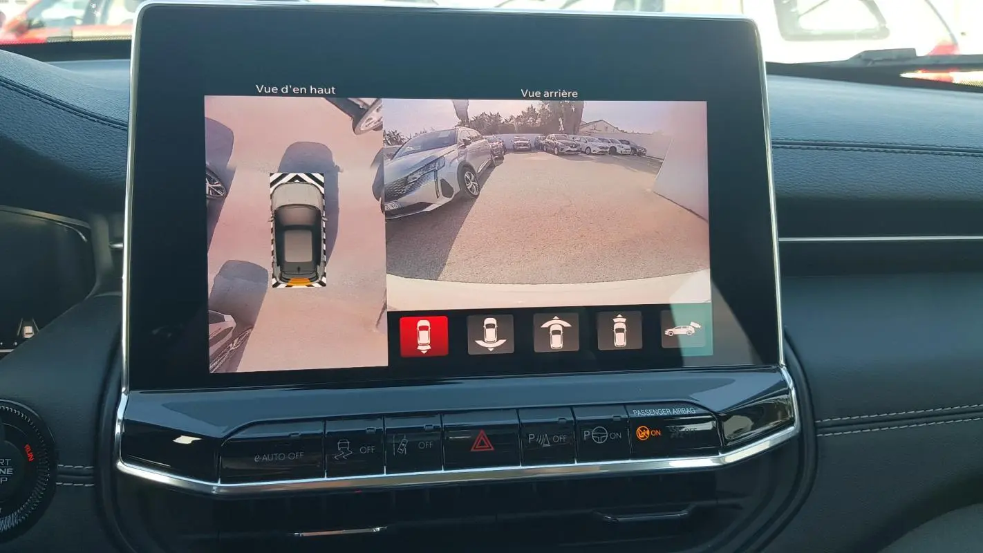 Écran tactile intérieur montrant la caméra de recul et la vue aérienne du Jeep Compass blanc 2024.