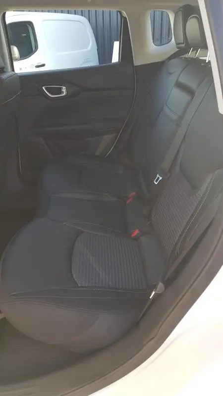 Vue intérieure côté gauche des sièges arrière noirs du Jeep Compass blanc 2024 avec ceinture de sécurité visible.