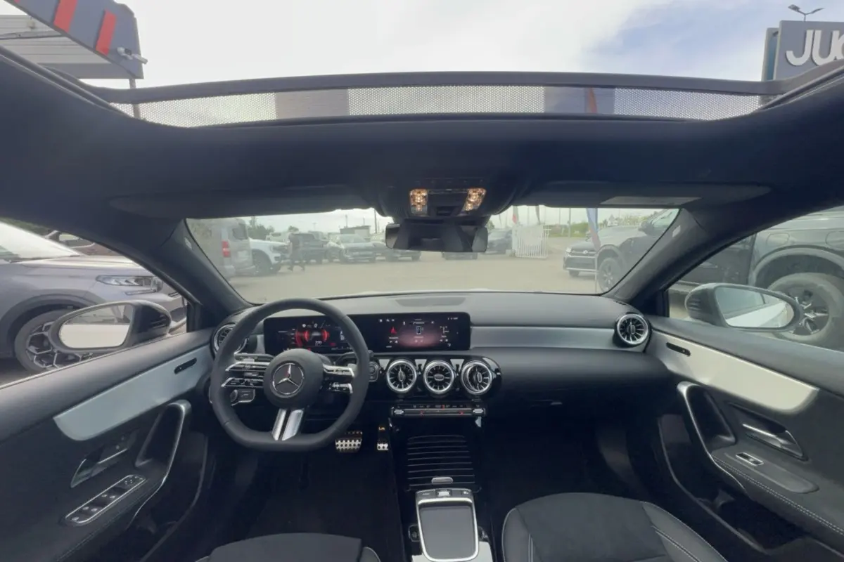 Vue intérieure avant de la Mercedes Classe A 200D BVA Exclusive Design 2026 avec tableau de bord noir et toit ouvrant panoramique.