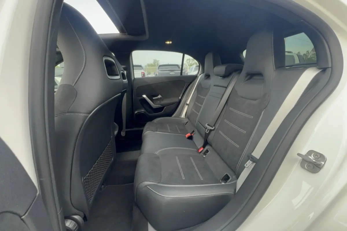 Vue intérieure arrière côté droit de la Mercedes Classe A 200D Exclusive Design avec sellerie cuir tissu noire et portières blanches.