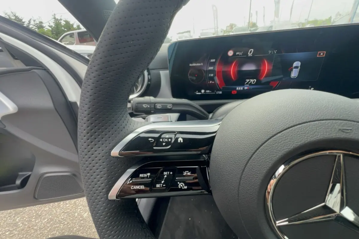 Gros plan sur le volant cuir multifonctions et le tableau de bord numérique de la Mercedes Classe A 200D blanc polaire.