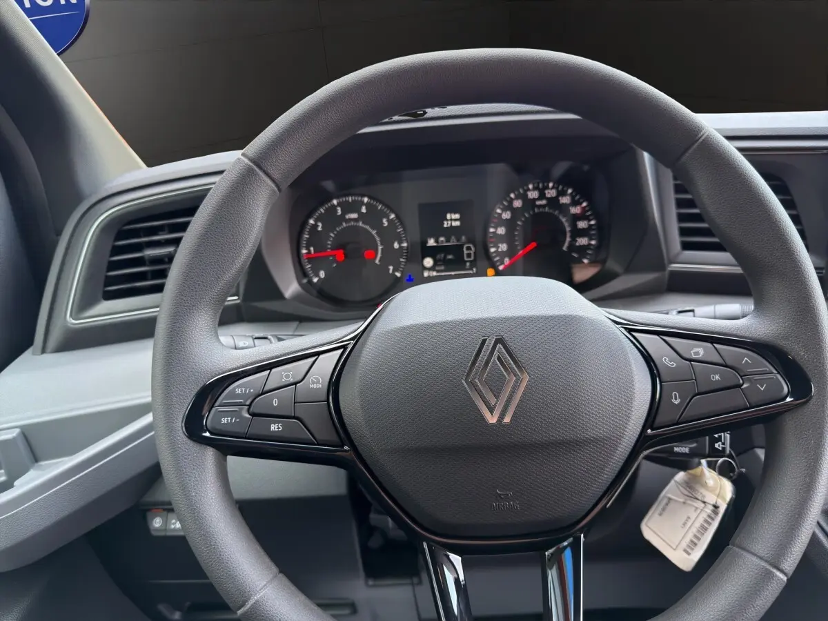 Vue rapprochée du volant multifonctions gris du Renault Master 2026 avec tableau de bord numérique en arrière-plan.