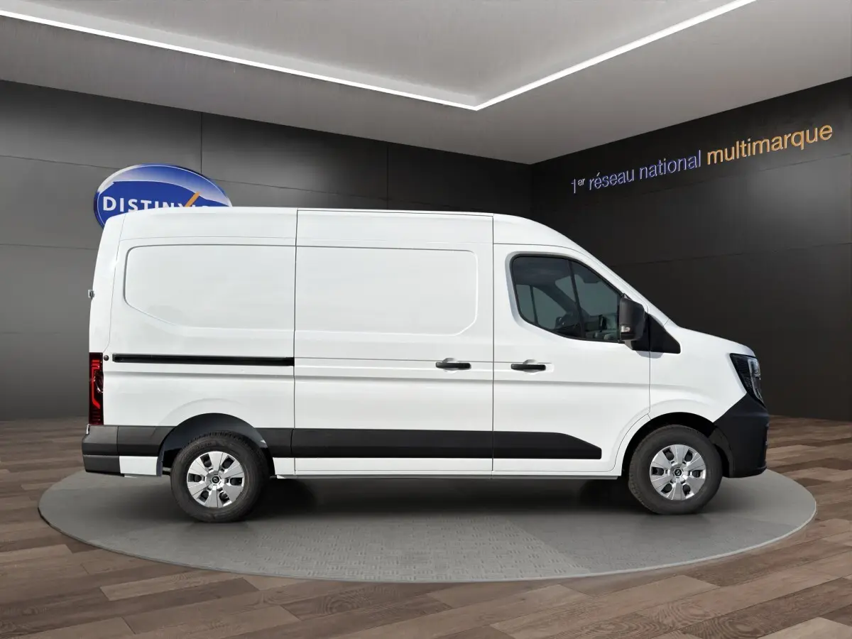 Vue de profil côté droit du Renault Master blanc avec bande noire et jantes argentées en showroom.