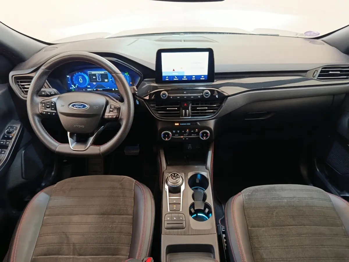 Vue intérieure avant du Ford Kuga 2023 gris foncé, tableau de bord moderne avec écran tactile central et volant multifonctions.