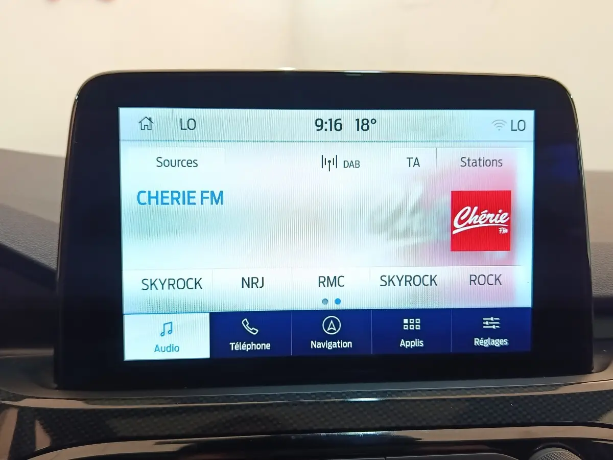 Écran tactile central du Ford Kuga 2023 affichant les stations radio, interface claire en intérieur noir.