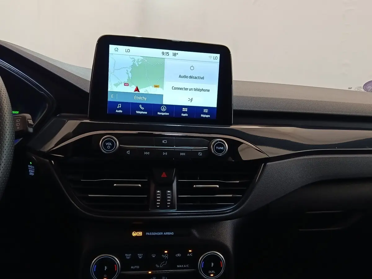 Tableau de bord noir du Ford Kuga 2023 avec écran tactile central affichant la navigation, vu de face.